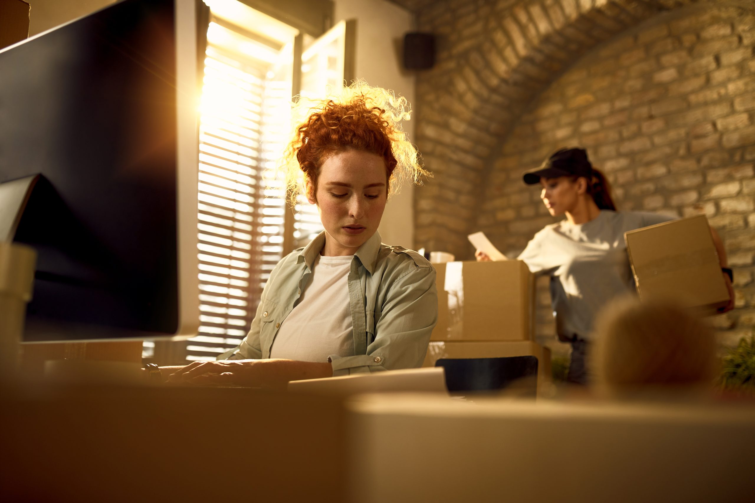 Young woman updating order details while preparing packages for a delivery in the office.